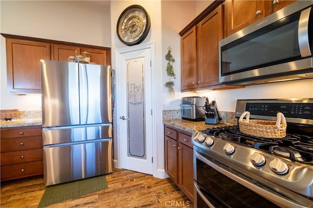 kitchen with light stone counters, stainless steel appliances, and dark wood-type flooring