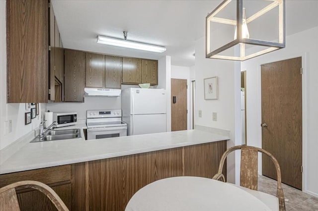 kitchen with white appliances, kitchen peninsula, sink, and hanging light fixtures