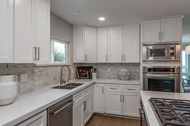 kitchen featuring sink, decorative backsplash, white cabinets, and appliances with stainless steel finishes