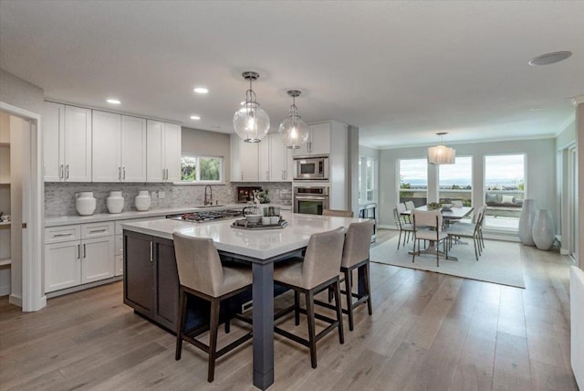 kitchen featuring white cabinetry, appliances with stainless steel finishes, a center island, and decorative light fixtures