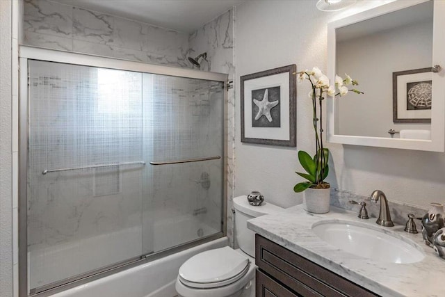 full bathroom featuring vanity, combined bath / shower with glass door, and toilet