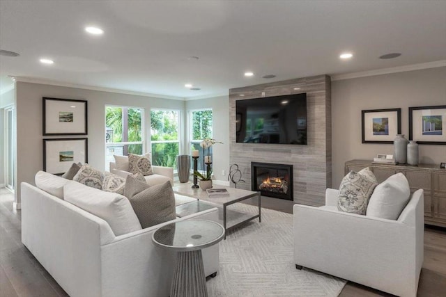 living room with crown molding, a fireplace, and light hardwood / wood-style flooring