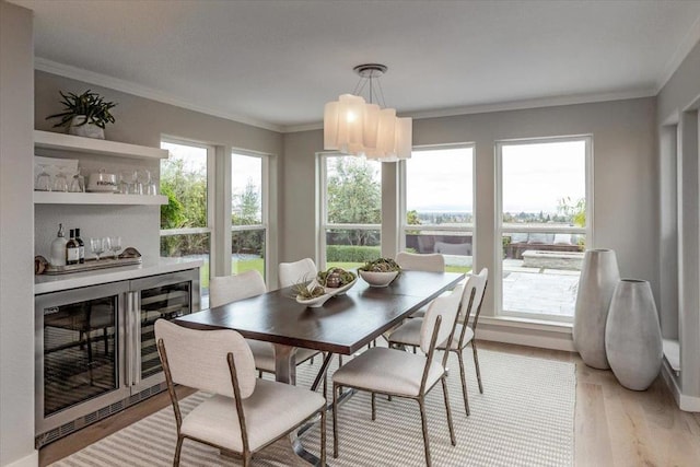 dining area featuring crown molding, bar, beverage cooler, and light hardwood / wood-style flooring