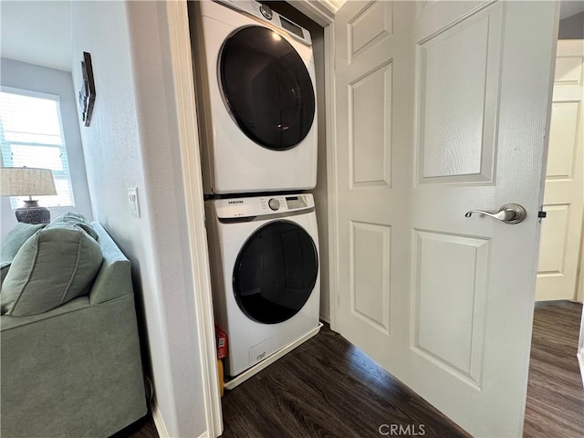 laundry room with dark wood-type flooring and stacked washer and clothes dryer