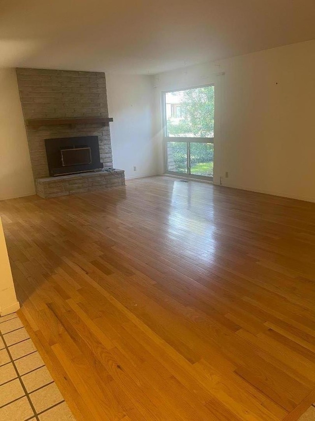 unfurnished living room with a brick fireplace and light hardwood / wood-style flooring