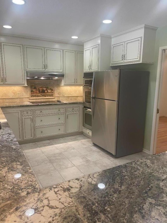 kitchen with tasteful backsplash, appliances with stainless steel finishes, and dark stone counters