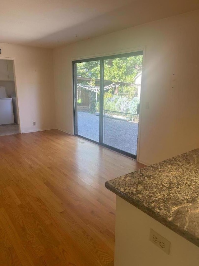 unfurnished living room featuring washer / dryer and light hardwood / wood-style flooring