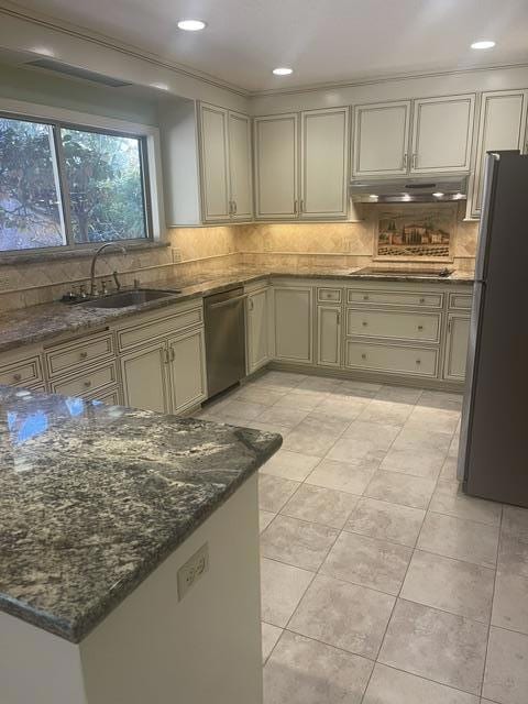 kitchen featuring appliances with stainless steel finishes, sink, decorative backsplash, and dark stone counters