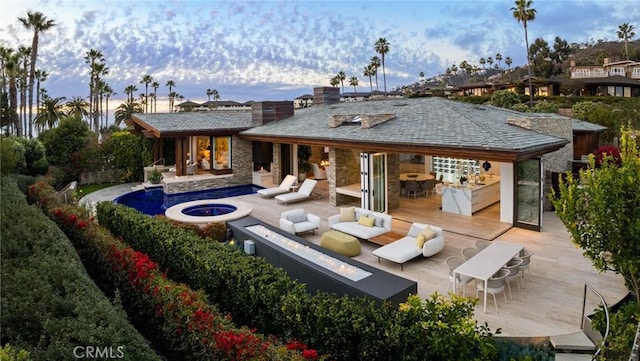 back house at dusk with an outdoor living space with a fire pit