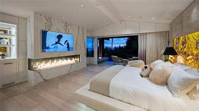 bedroom featuring lofted ceiling with beams, light hardwood / wood-style flooring, and access to outside