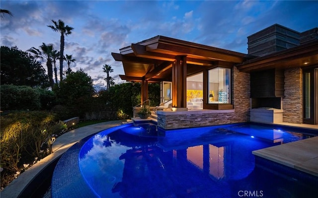 pool at dusk with a patio area