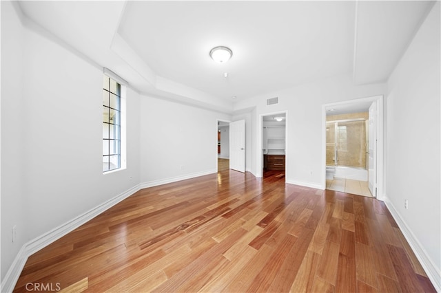 unfurnished bedroom with hardwood / wood-style flooring, a walk in closet, ensuite bath, and a closet