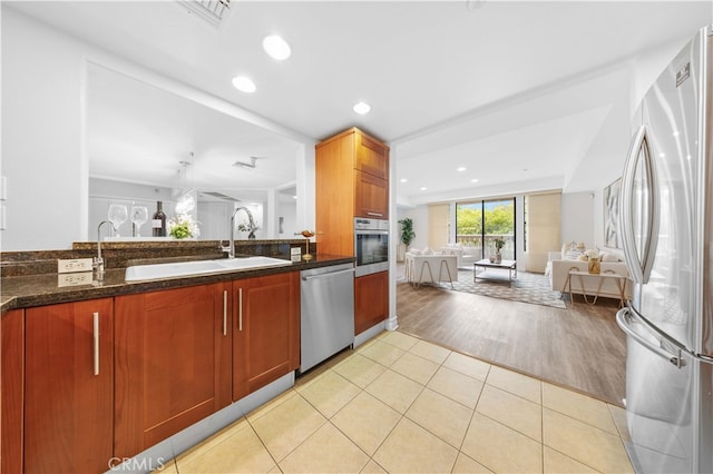 kitchen featuring light tile patterned flooring, appliances with stainless steel finishes, sink, and dark stone countertops