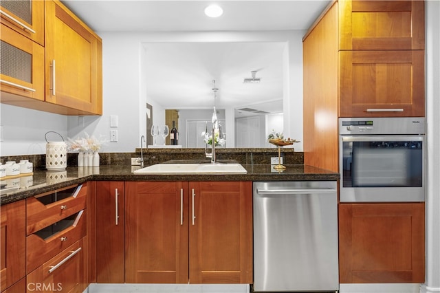 kitchen featuring decorative light fixtures, appliances with stainless steel finishes, sink, and dark stone counters