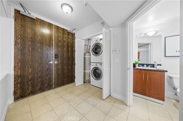 clothes washing area featuring stacked washer / dryer, strapped water heater, sink, and light tile patterned floors