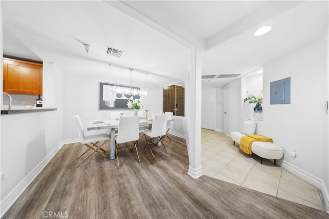 dining room with electric panel and light wood-type flooring