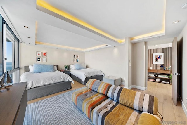 bedroom with a tray ceiling and light hardwood / wood-style floors