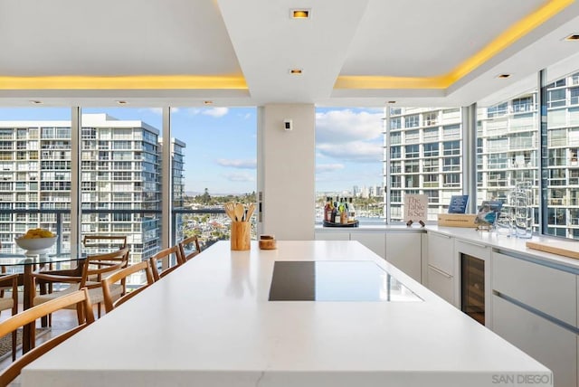 kitchen with cooktop, a spacious island, white cabinets, and a tray ceiling