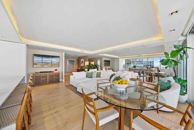 dining area with a raised ceiling and light wood-type flooring