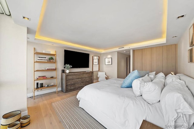 bedroom featuring light hardwood / wood-style flooring and a raised ceiling