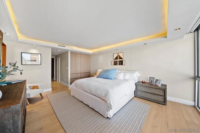 bedroom with a tray ceiling and light hardwood / wood-style flooring