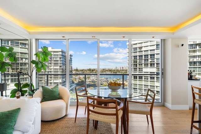 dining area featuring a water view, a wall of windows, and hardwood / wood-style floors