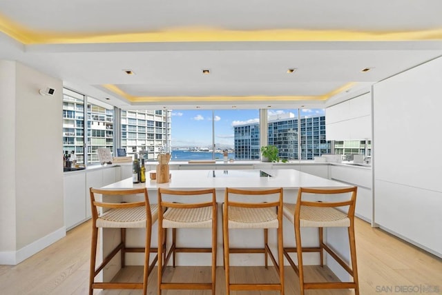 kitchen featuring a water view, white cabinetry, a kitchen island, and a breakfast bar