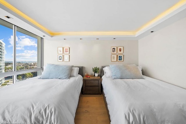 bedroom with a tray ceiling and light wood-type flooring