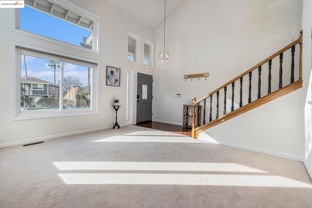 carpeted foyer entrance featuring high vaulted ceiling and a notable chandelier