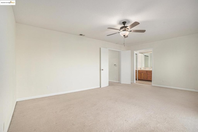 unfurnished bedroom featuring ceiling fan, light colored carpet, and ensuite bath