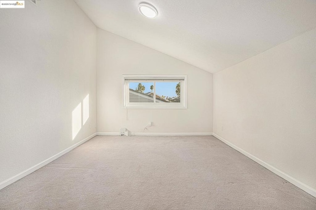 spare room with vaulted ceiling and light colored carpet