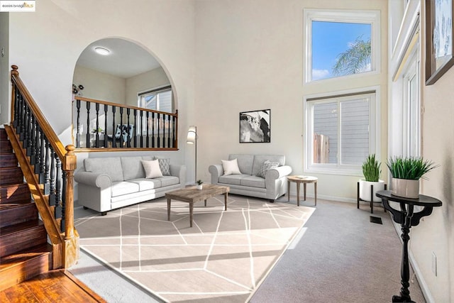 carpeted living room featuring a towering ceiling