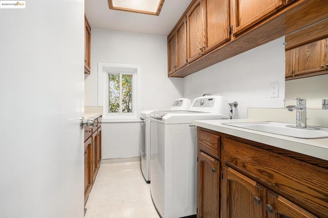 clothes washing area featuring cabinets, sink, and washing machine and dryer