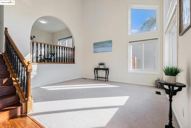 interior space with a towering ceiling, carpet floors, and a healthy amount of sunlight