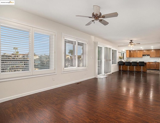 unfurnished living room with dark wood-type flooring and ceiling fan