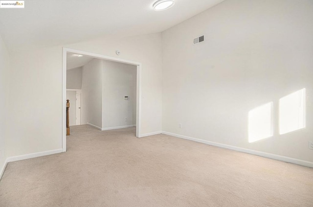 spare room with light carpet and vaulted ceiling