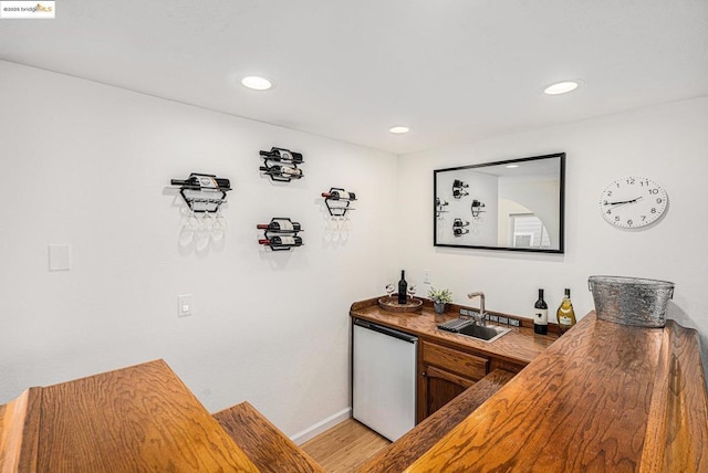 bar with dishwasher, sink, and light wood-type flooring