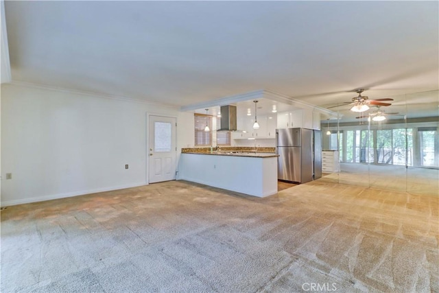 kitchen with white cabinetry, light carpet, hanging light fixtures, stainless steel fridge, and kitchen peninsula