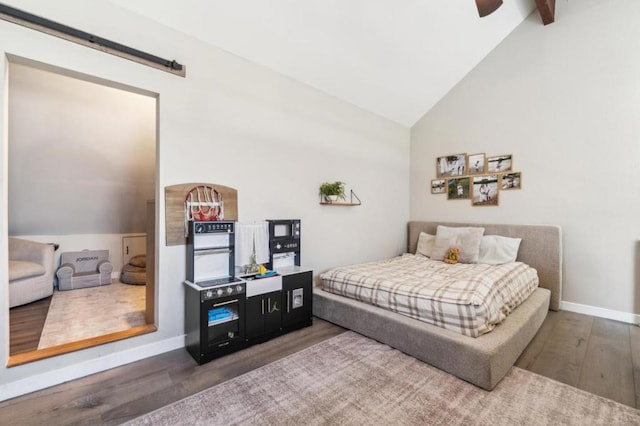 bedroom with ceiling fan, wood-type flooring, a barn door, and high vaulted ceiling