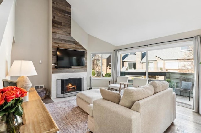 living room featuring a premium fireplace, high vaulted ceiling, and light wood-type flooring