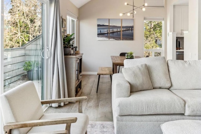 living room with lofted ceiling, hardwood / wood-style floors, and an inviting chandelier