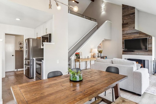 dining room with a fireplace, high vaulted ceiling, and light hardwood / wood-style flooring