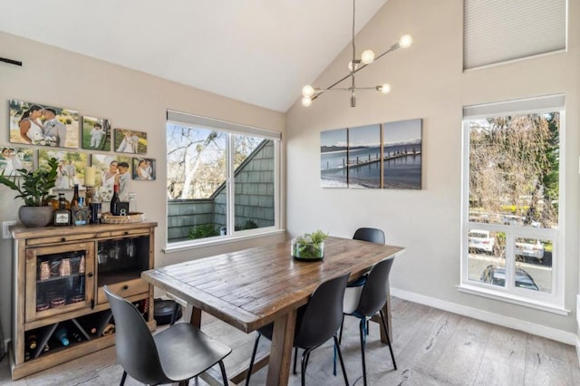 dining space with hardwood / wood-style flooring, lofted ceiling, and a notable chandelier