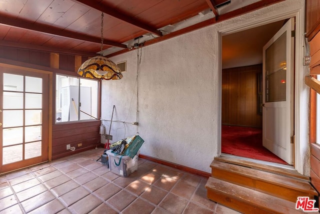 unfurnished sunroom featuring beamed ceiling and wooden ceiling