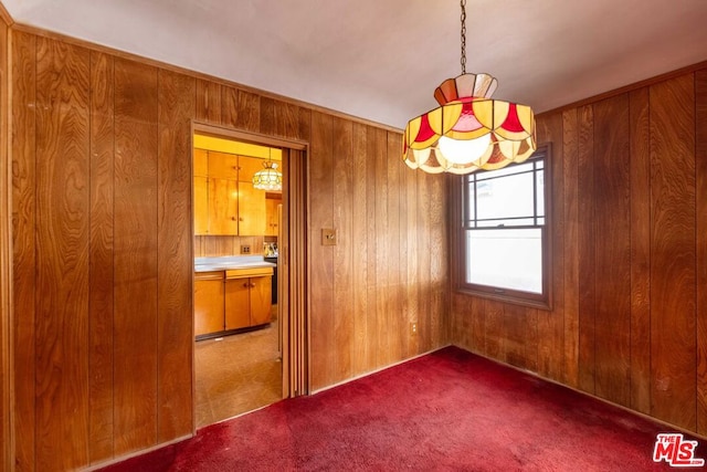 carpeted empty room featuring wood walls