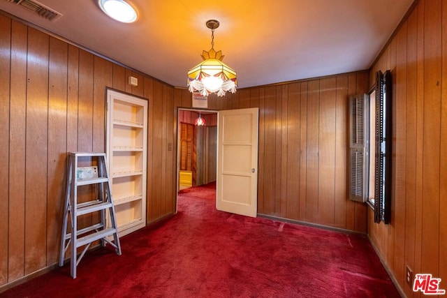 empty room with wooden walls, dark carpet, and built in features