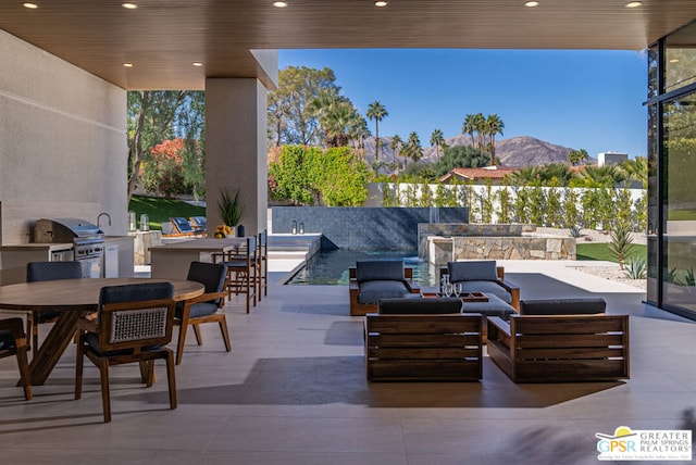 view of patio featuring exterior kitchen, grilling area, an outdoor living space, and a mountain view