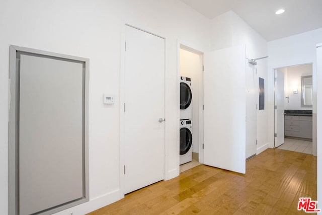 laundry area with hardwood / wood-style floors, electric panel, and stacked washer and clothes dryer