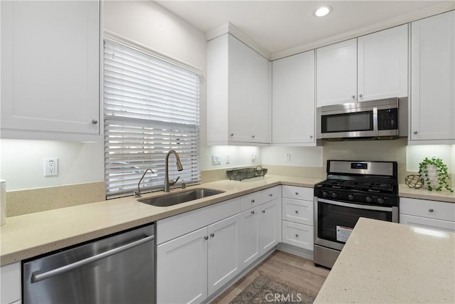 kitchen with appliances with stainless steel finishes, white cabinets, and a sink