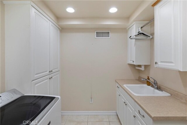 laundry area featuring cabinets, light tile patterned flooring, washer / dryer, and sink